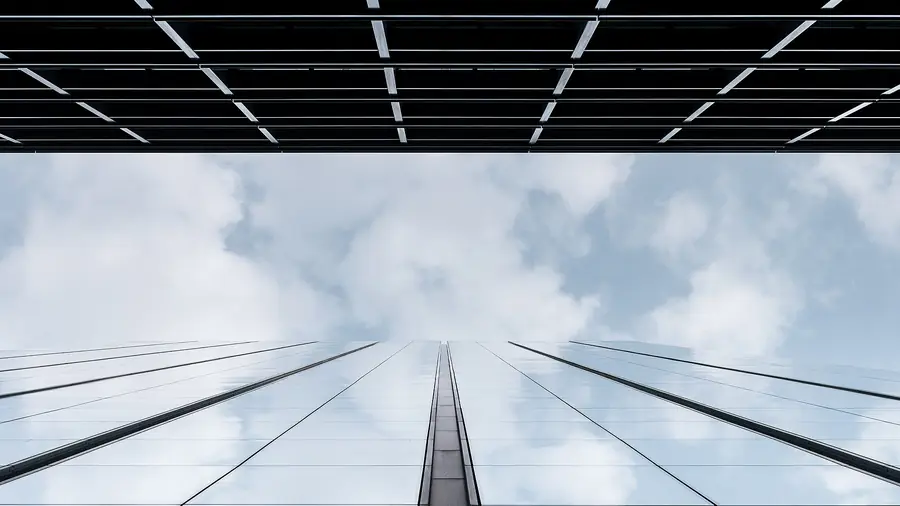 Glass office facade reflecting clouds